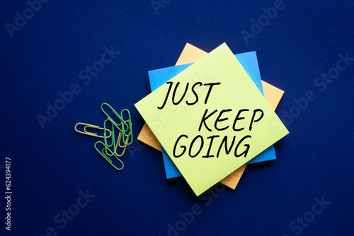 Just keep going symbol. Yellow steaky note with words Just keep going. Beautiful deep blue background. Business and Just keep going concept. Copy space. photo