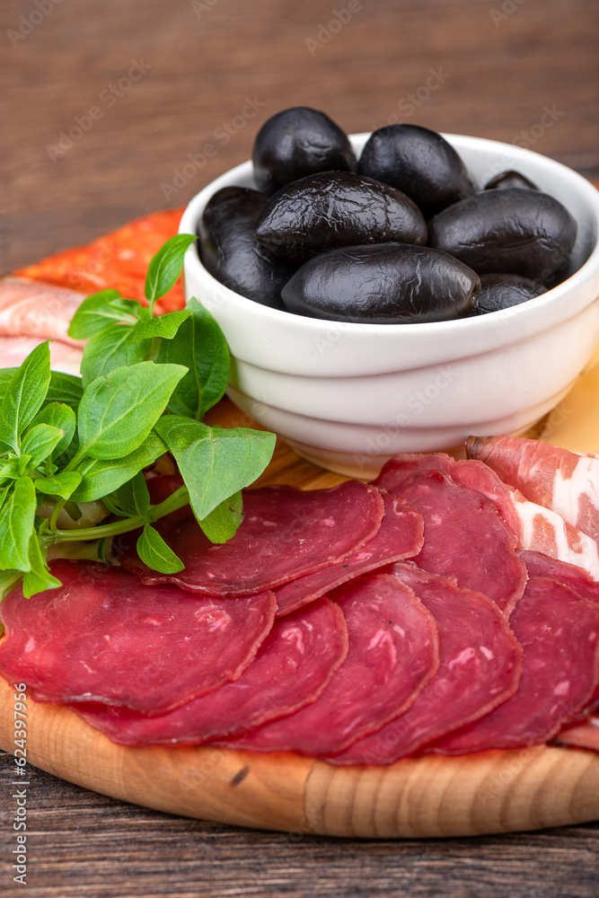 Close-up of sliced pastrami, black olives and green basil. Close-up of sliced pastrami, black olives and green basil.
