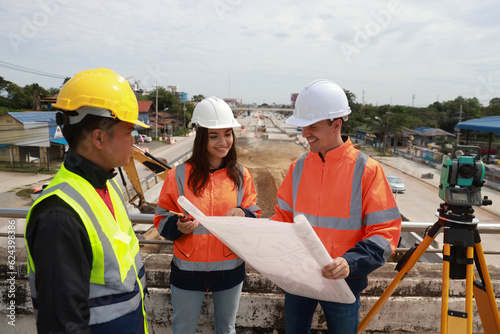 A civil team of engineers works with a blueprint at the  Construction Site of New Concrete Roads and Bridges