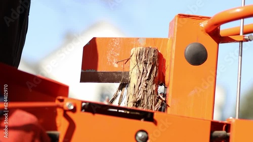 Hydraulic wood splitter cutting wood on a sunny day. 4K Video