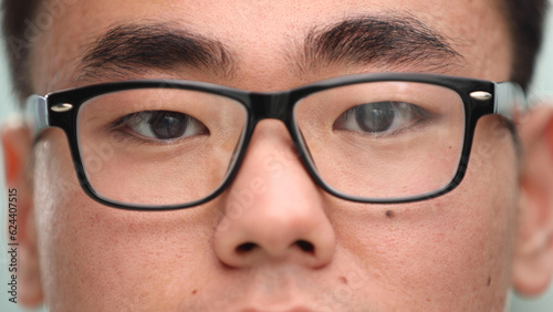 Quadro su tela Close-up of a focused Asian businessman, wears glasses to reduce eye strain