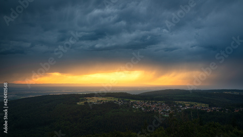 Golden sunset over the upper Rhine plain while a summer thunderstorm passes over the northern Black Forest