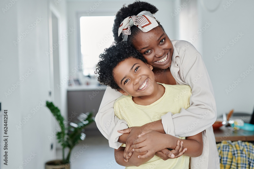 Obraz premium Portrait of happy mom embracing her little son and they smiling at camera together at home