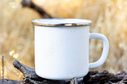 Blank white enamel coffee cup mockup, camping mug in forest.