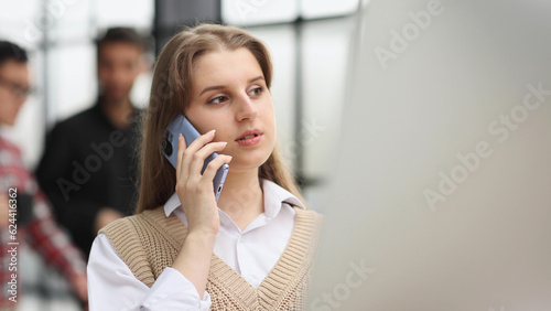 serious young woman talking on smartphone in the office.