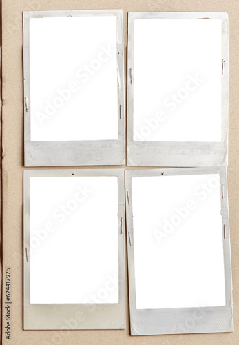 A vintage book page with blank instant photo frames attached with staples.