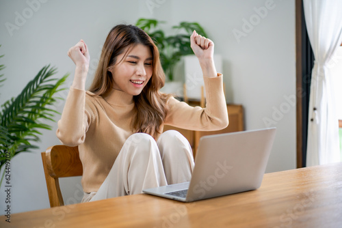 Happy young Asian Woman Successful working with laptop checking happy congrats get good news Young asian feel excited and colleague student passed exam.