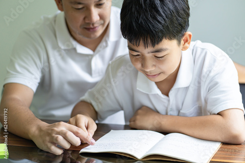 Asian father helps son to do her homework for the school..child study together homeschooling concept getting homework help from father
