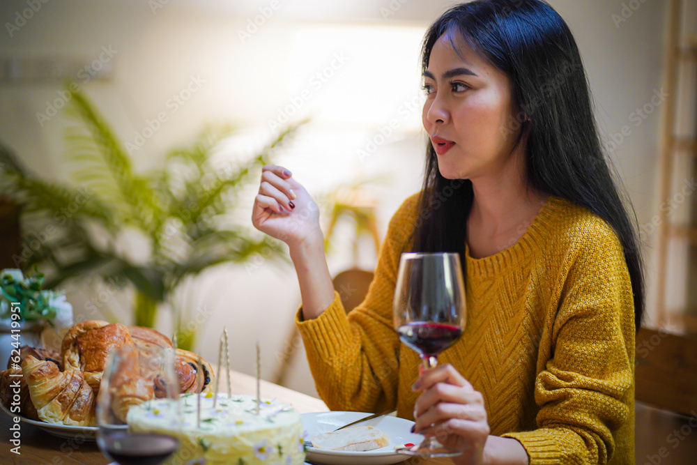 Cheerful friends enjoying home Birthday holiday party. Asian sister cheering drinking red wine celebrating with Birthday cake Cheerful friends enjoying home Birthday holiday party. Asian sister cheering drinking red wine celebrating with Birthday cake