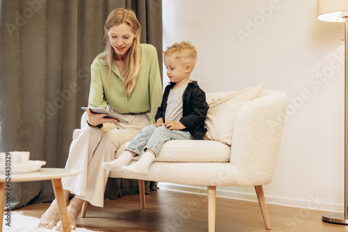 Woman sitting with her son and using tablet playing games