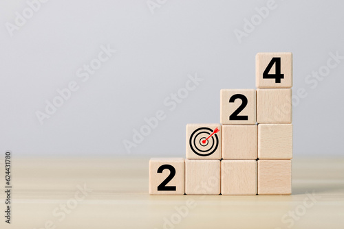 Businessman showing 2024 goal plan execution, business planning and strategic concept. Analysis of financial markets, investment growth and success on wooden blocks.