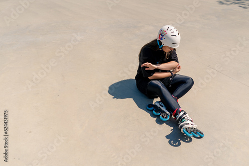 upset girl in protective helmet and rollerblades checks hands after fall active recreation skating sport hobby