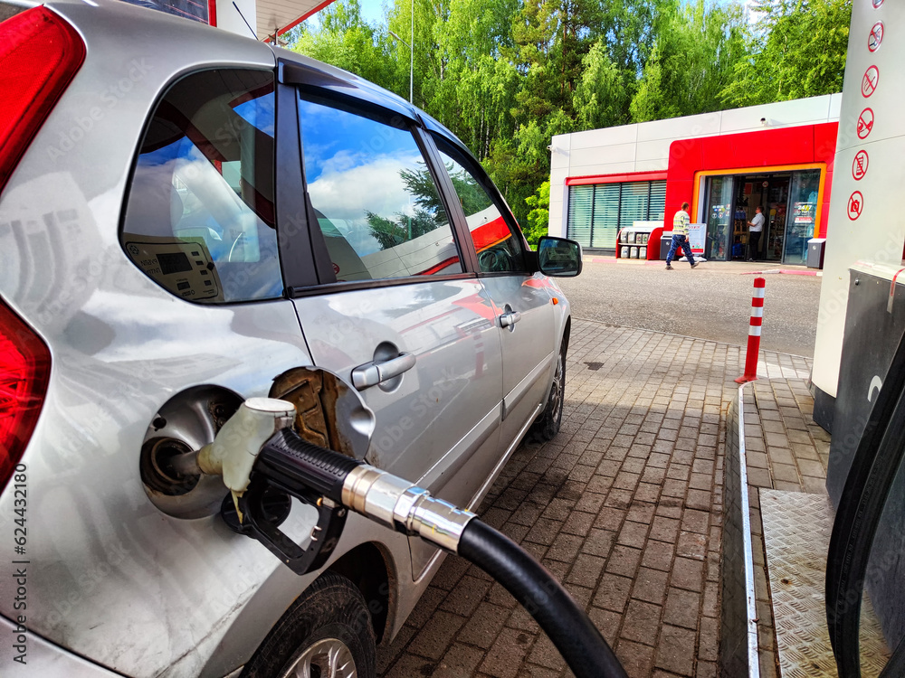 Gasoline filling station, car, and fuel nozzle inserted into the fuel tank. Refueling a car with gasoline at gas station. The concept of traveling by car. Fuel shortage Gasoline filling station, car, and fuel nozzle inserted into the fuel tank. Refueling a car with gasoline at gas station. The concept of traveling by car. Fuel shortage