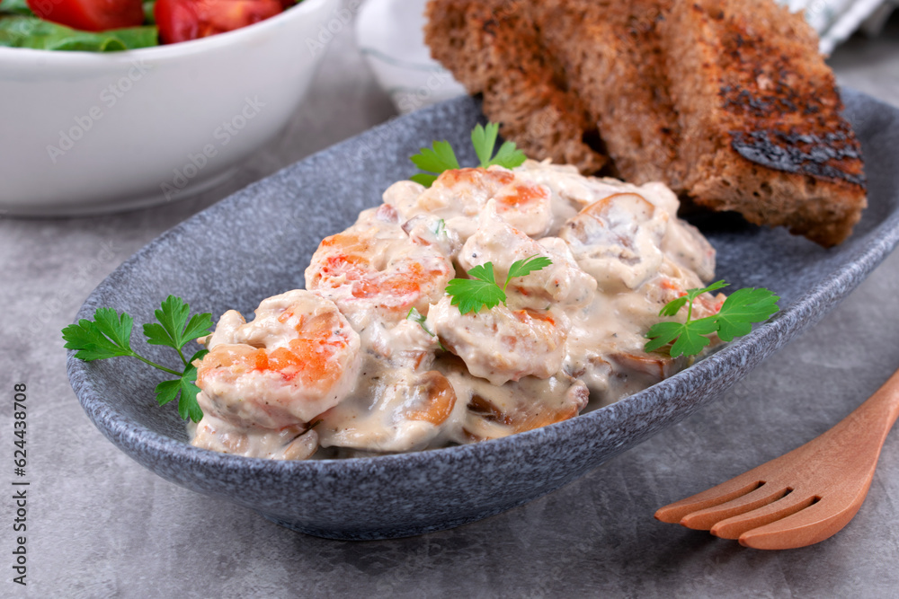 Shrimps in creamy sauce with champignons served on a plate with toasted bread and salad. Seafood meal Shrimps in creamy sauce with champignons served on a plate with toasted bread and salad. Seafood meal