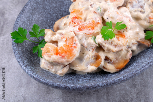 Shrimps in creamy sauce with champignons served on a plate. Seafood meal 