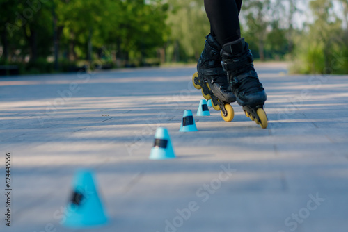 sporty girl practicing tricks on roller skates in park on city background enjoying roller skating lesson with chips close-up Street sports concept