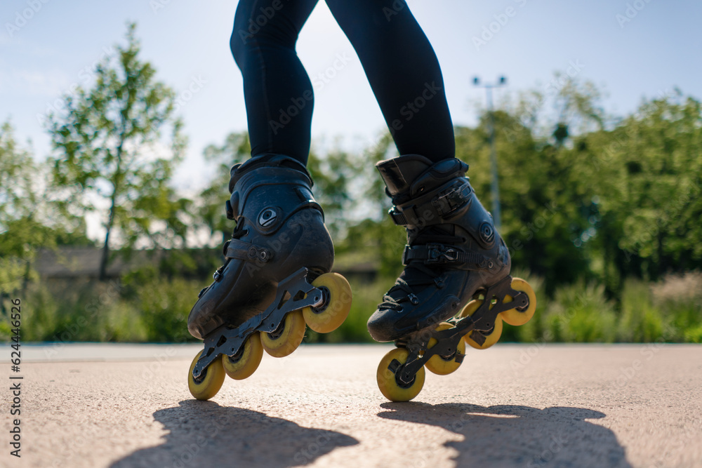 Obraz premium sporty girl practicing tricks on roller skates in park on city background enjoying roller skating lesson close up legs street sport