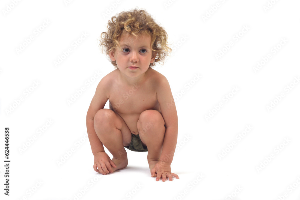 front view of a boy in underpants squatting and  looking away on white background (3 year old)