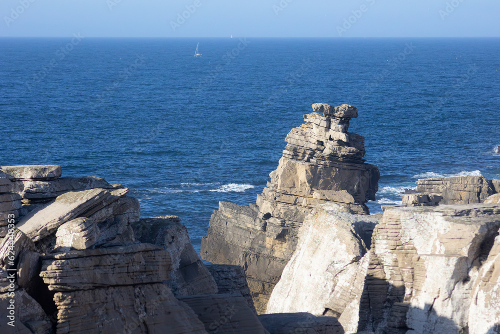 rochas na costa com um iate ao fundo