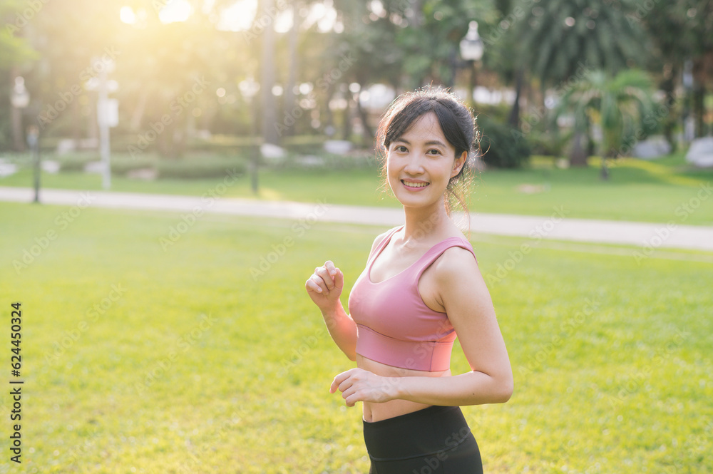Capture the happiness of a young, beautiful Asian woman in her 30s as she smiles and looks at the camera in a park at sunset. Experience the concept of wellness living. Capture the happiness of a young, beautiful Asian woman in her 30s as she smiles and looks at the camera in a park at sunset. Experience the concept of wellness living.