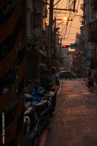 Pedestrians and motor vehicles crowded in the narrow alleyway under the sunset photo