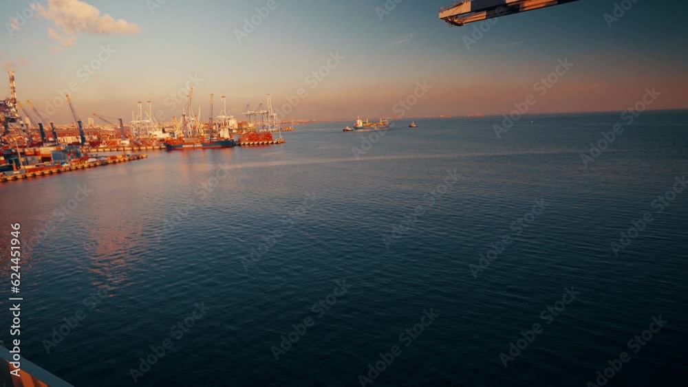 4K wide angle shot from slowly sailing ship on sea. Coastline, port, cranes seen from vessel in daylight stock video 4K wide angle shot from slowly sailing ship on sea. Coastline, port, cranes seen from vessel in daylight stock video