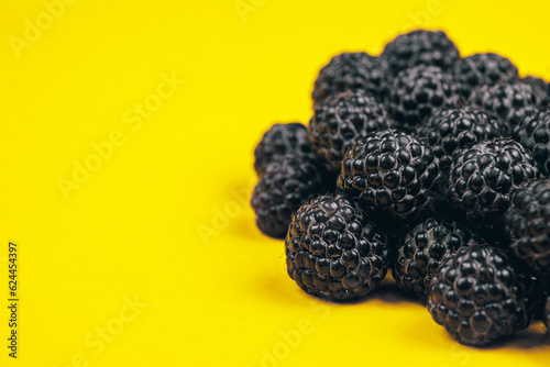 Heap of fresh ripe and sweet raspberries on yellow background. Black raspberries. Macro shot.