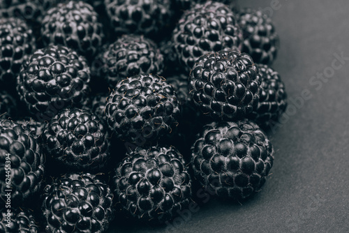 Heap of fresh ripe and sweet raspberries on gray background. Black raspberries. Macro shot.