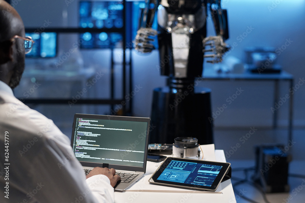 Rear view of engineer typing security codes on laptop to develop