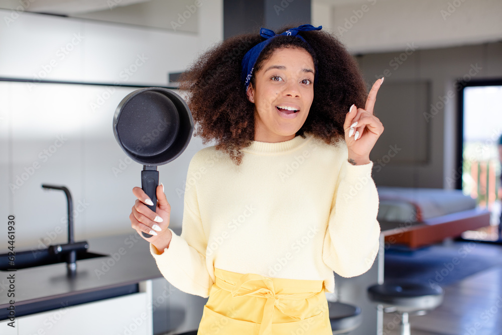 pretty afro black woman feeling like a happy and excited genius after realizing an idea. home chef concept