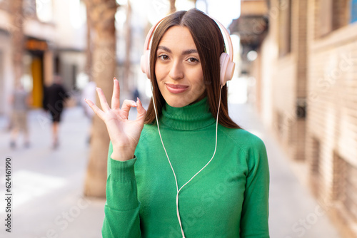 feeling happy  showing approval with okay gesture. listening music with headphones