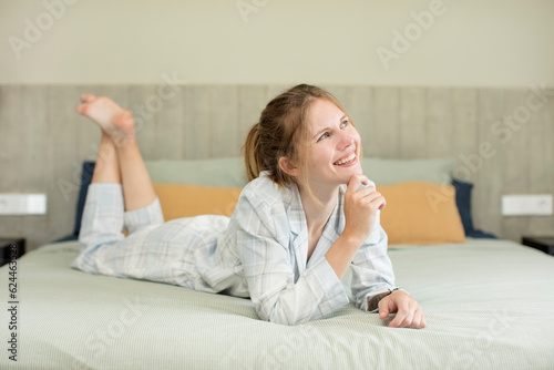 young pretty woman smiling with a happy, confident expression with hand on chin. nightwear concept