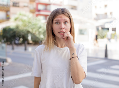 pretty young woman with surprised, nervous, worried or frightened look, looking to the side towards copy space