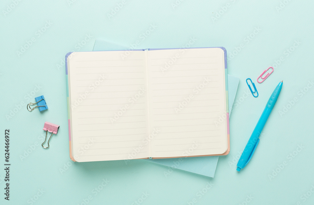 Open notebook with stationery on color background, top view Open notebook with stationery on color background, top view