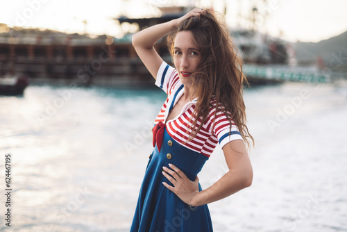 a beautiful sexy girl in a sea uniform walks on the beach against the background of ships. © Tsyb Oleh