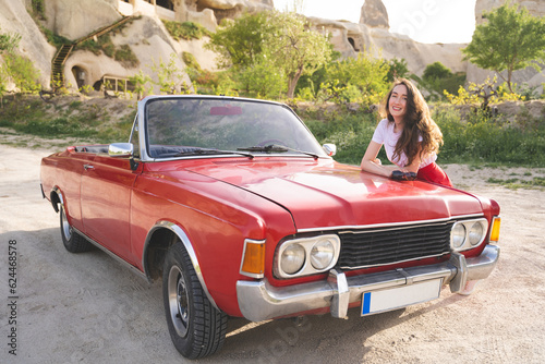 beautiful happy girl in a skirt posing near a retro car in the mountains of cappadocia