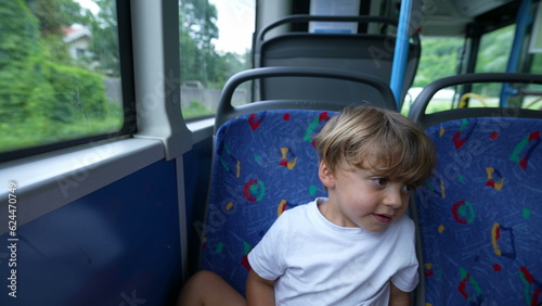 Child staring out bus window traveling by public transportation