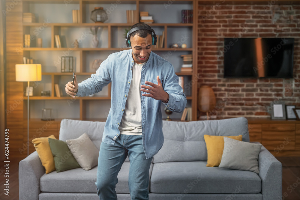 Handsome young man dancing and listening to music at home