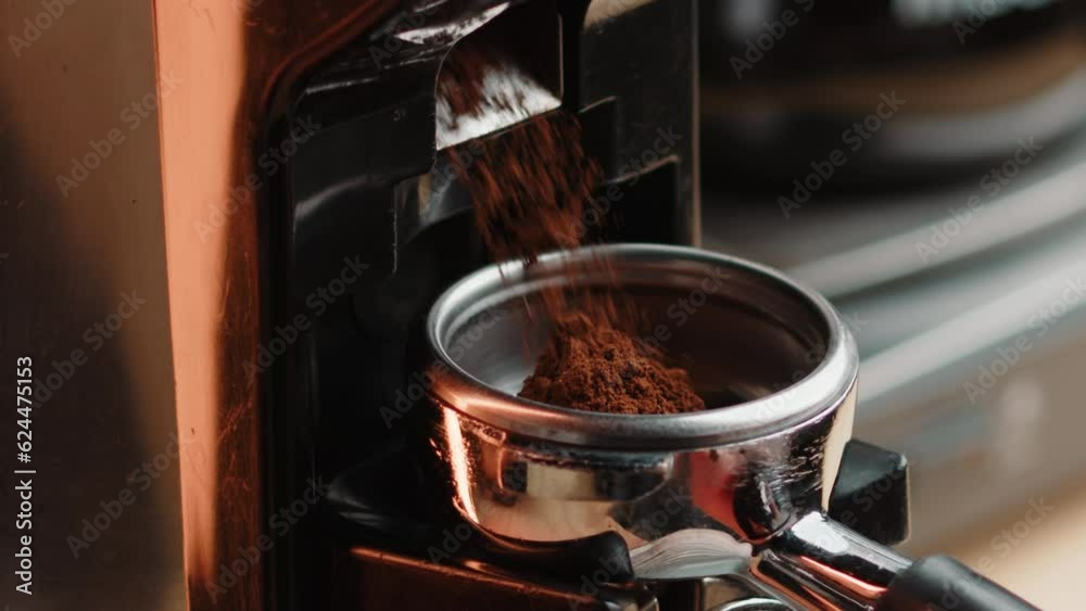 Professional barista worker use grinder machine to grind fresh coffee beans for make hot beverage cafe table. Extreme close up macro shot