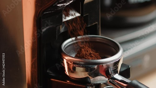 Professional barista worker use grinder machine to grind fresh coffee beans for make hot beverage cafe table. Extreme close up macro shot