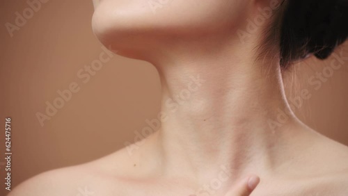Close-up of a beauty asian young woman touches her neck, on beige background. Beautiful female model with perfect clean fresh skin. Skin care treatment concept
