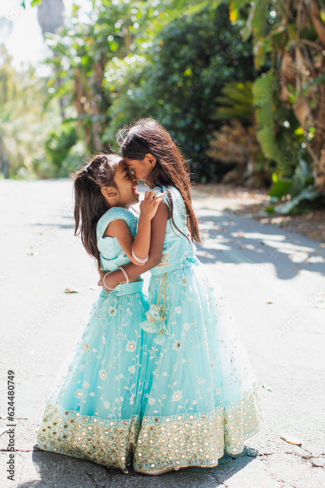 beautiful indian family smiling with a bindi and traditional sari dress sisters girls in front of greenery and palm trees nose to nose beautiful indian family smiling with a bindi and traditional sari dress sisters girls in front of greenery and palm trees nose to nose