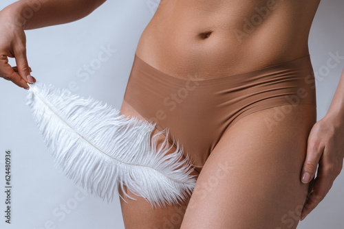 Female belly and soft feather. Concepts of body cosmetics and  hair removal treatment photo