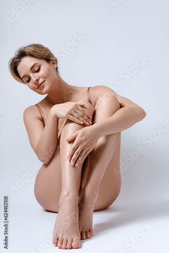 Young attractive woman wearing brown lingerie is happy with her body and smooth skin