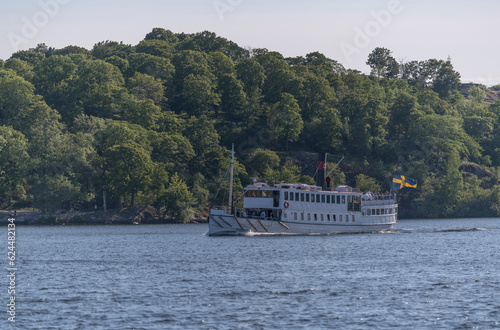 Old steam passenger boat arriving the down town from the island Drottningholm, a sunny summer evening in Stockholm