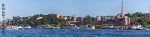 Panorama, tourist steam boat and modern ferries, industrial brick buildings, , hill Maria. district Södermalm, moored old fishing and hotel boats, a sunny summer evening in Stockholm