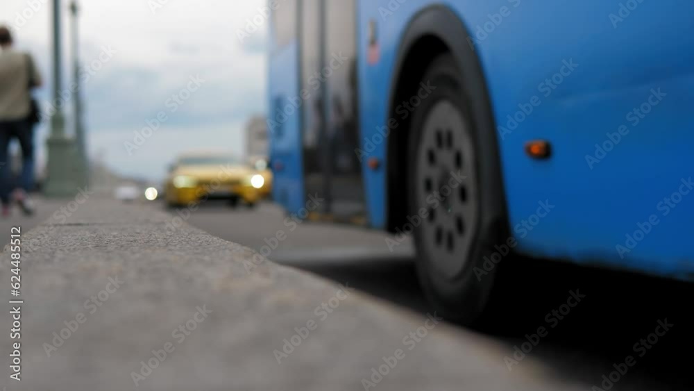 Close-up of a blurry big blue bus driving along a busy road in a megalopolis. A blurry image of the road and passing cars.