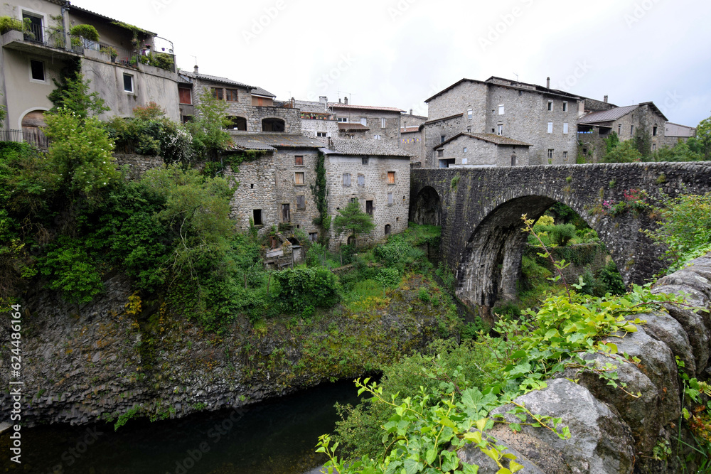 
Jaujac village in Ardeche, Massif Central, France, in the rain without people - dark, volcanic stone and flowing river under ancient stone bridge