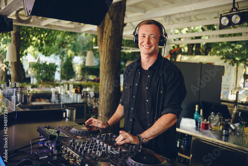 Smiling dj at work in a summer restaurant.