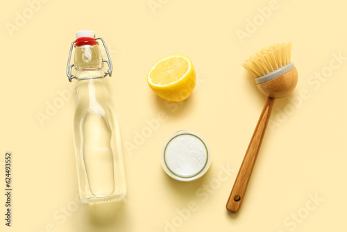 Bottle of vinegar  baking soda  brush and lemon on color background